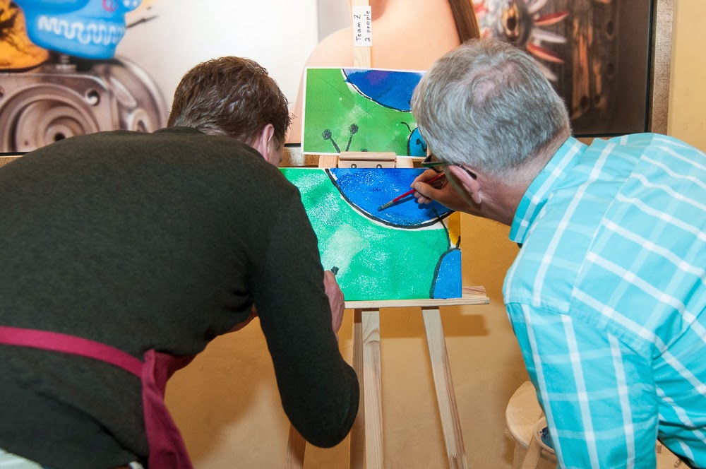 A pair of employees works on a painting during a workshop for an employee incentive program.