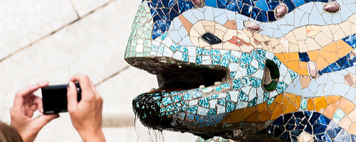 An image of a visitor taking a picture of the Gaudi lizzard at park Guell.